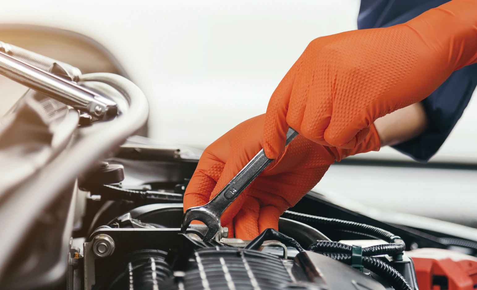 Orange disposable nitrile gloves used for vehicle component servicing
